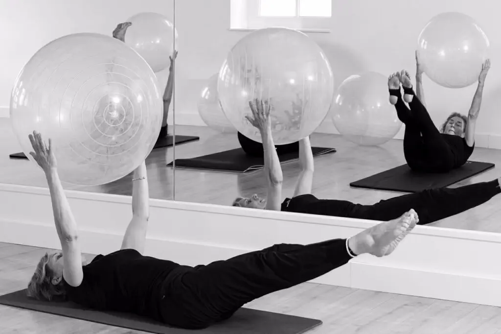Deelnemer voert Pilates oefeningen uit met een oefenbal voor verbeterde balans